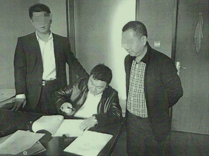 乐山市商业银行工作人员当年到工行应城支行面签时，殷学明（中）假冒银行工作人员在文件上盖章。 本文图片均由受访者提供